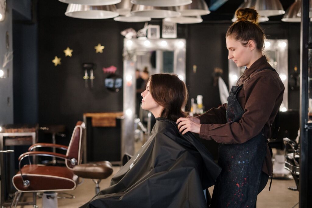 Thợ làm tóc cắt tóc cho khách ngồi trước gương tại salon
