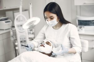 Chuyên viên đeo găng chăm sóc da mặt cho khách dưới đèn tại spa