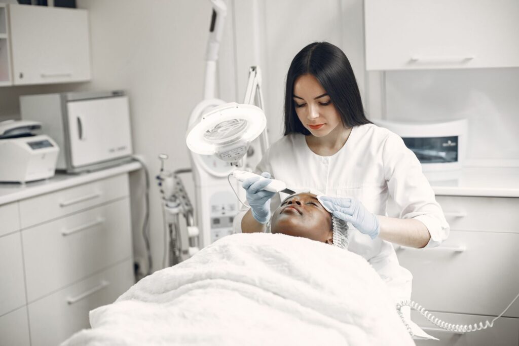 Chuyên viên chăm sóc da mặt cho khách nằm trên giường tại spa