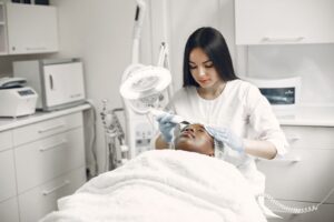 Chuyên viên chăm sóc da mặt cho khách nằm trên giường tại spa