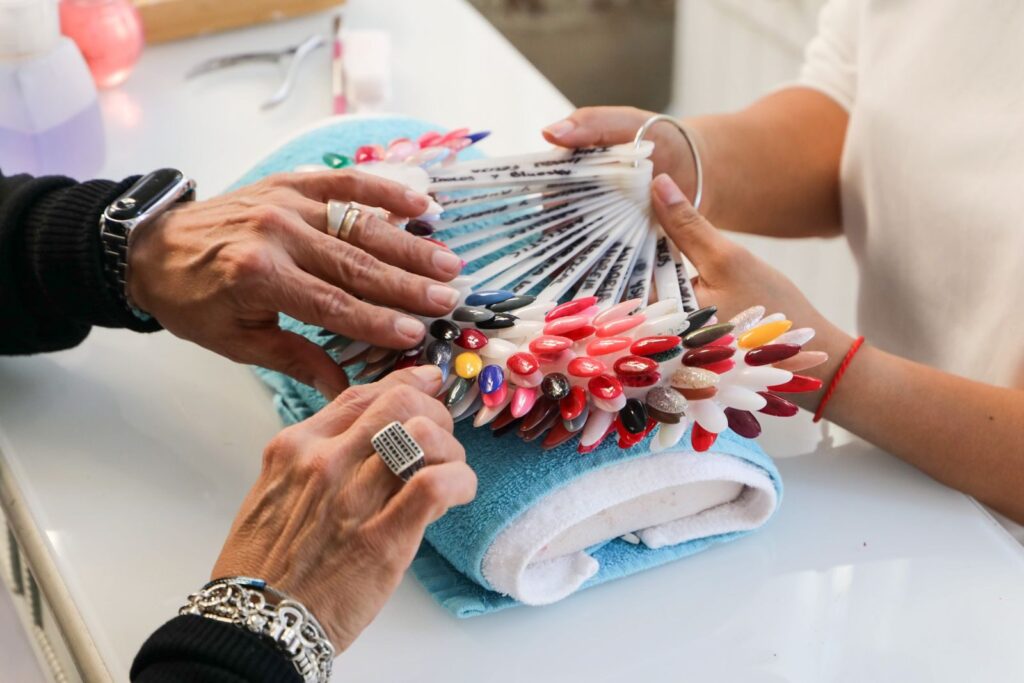 Khách và thợ nail xem bảng mẫu màu sơn móng tại bàn làm việc