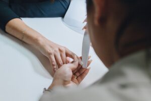 Thợ nail dùng dũa tạo dáng móng tay cho khách