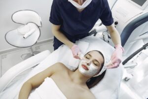 Chuyên viên đeo găng tay dùng miếng bông làm sạch mặt nạ cho khách