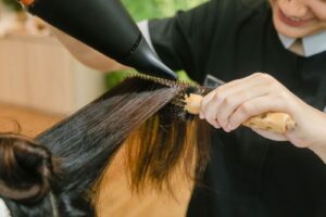 Thợ làm tóc dùng máy sấy và lược tròn tạo kiểu tóc