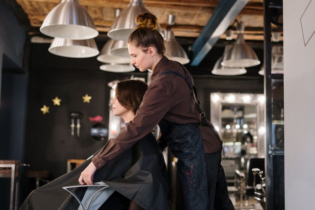 Thợ làm tóc chuẩn bị áo choàng cho khách tại salon