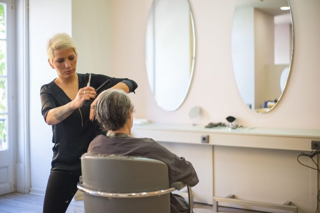 Thợ cắt tóc đứng sau khách trước gương salon