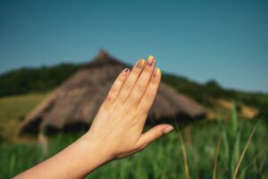 Bàn tay với móng trang trí trước khung cảnh đồng cỏ