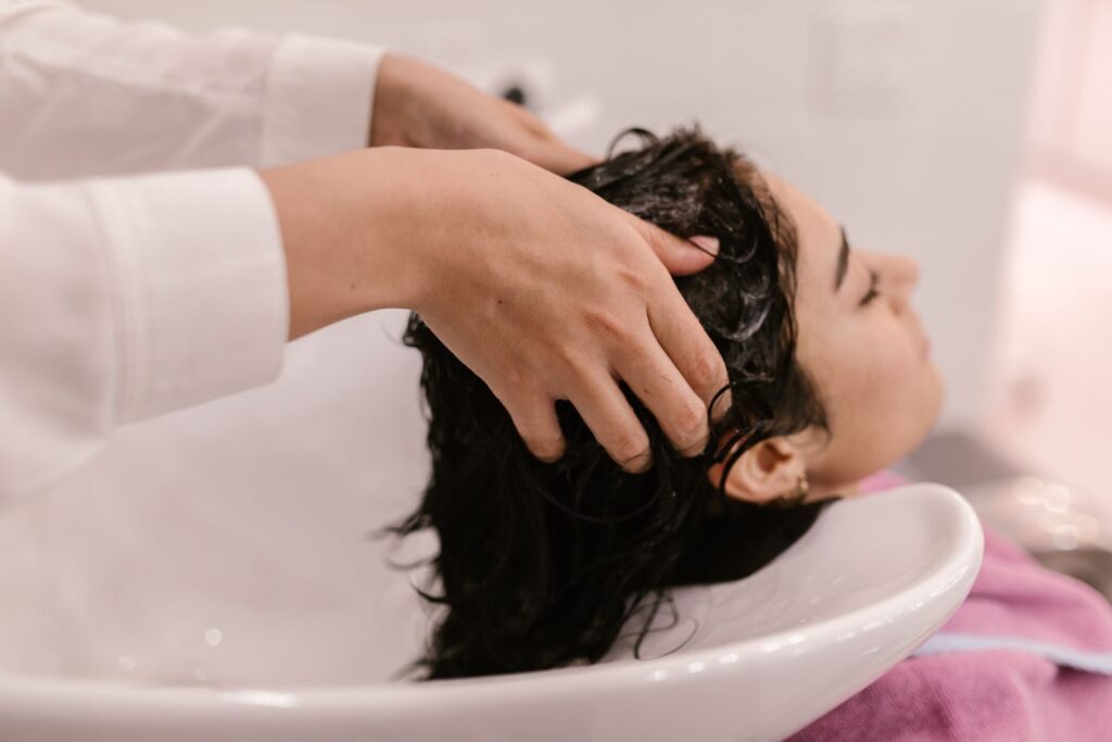Thợ gội đầu cho khách tại bồn gội trong salon
