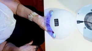 Bàn tay đeo vòng tay đặt trong đèn làm móng tại salon