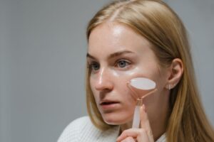 Người phụ nữ dùng cây lăn trên má trong lúc chăm sóc da mặt