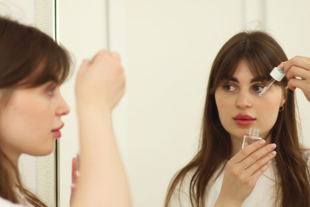 Người phụ nữ thoa serum chăm sóc da trước gương
