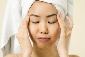 Người phụ nữ quấn khăn tóc và thoa sản phẩm chăm sóc da