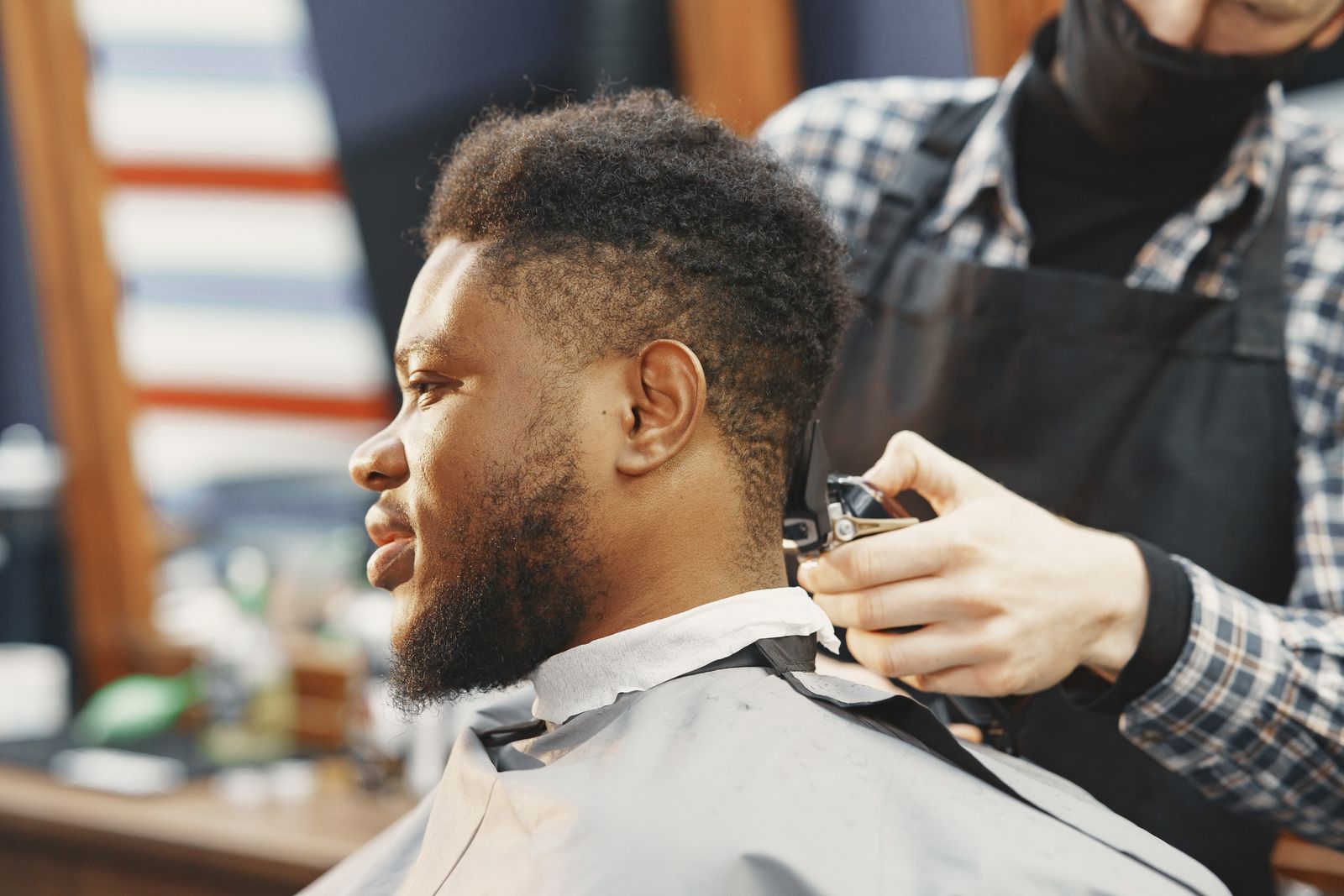 Thợ Barber dùng tông đơ cắt tóc cho một người đàn ông tại tiệm