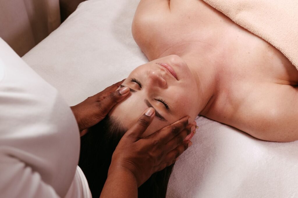 Chuyên viên dùng tay massage vùng trán cho khách đang nằm tại spa