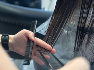 Thợ tóc dùng lược và kéo cắt một lọn tóc trong salon