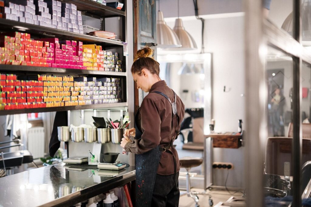 Thợ làm tóc sắp xếp sản phẩm trên kệ salon