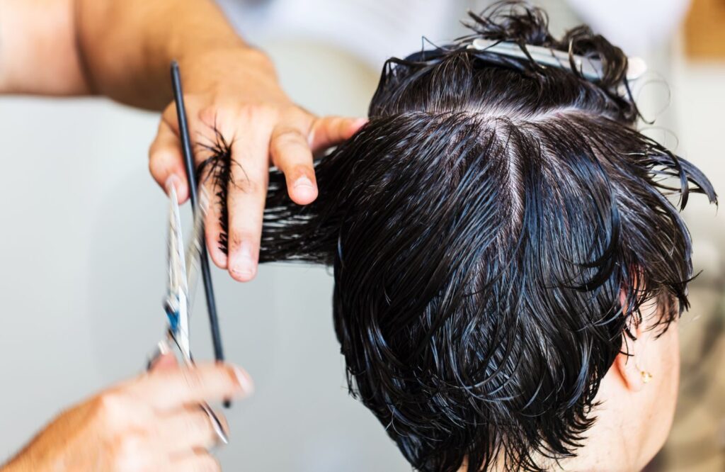 Thợ dùng kéo cắt tóc ướt cho khách tại salon