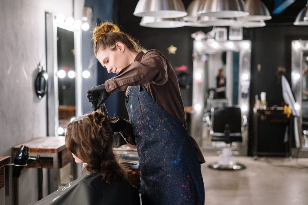 Thợ làm tóc thoa màu nhuộm lên tóc khách tại salon
