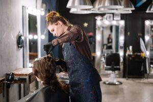 Thợ làm tóc thoa màu nhuộm lên tóc khách tại salon
