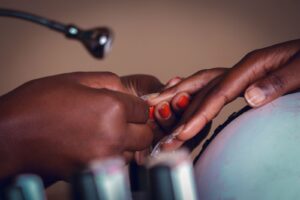 Cận cảnh thợ nail chăm sóc móng tay sơn đỏ cho khách